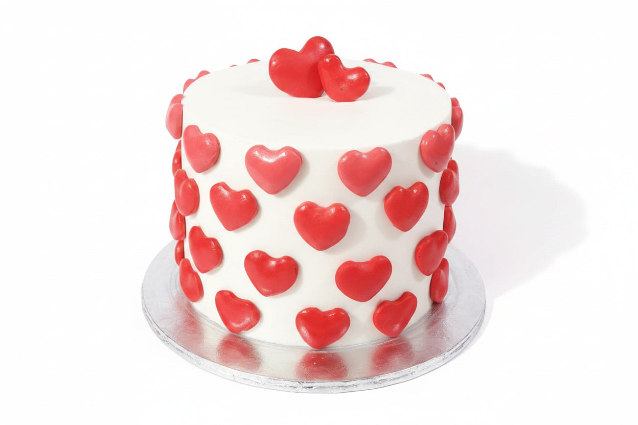 Anniversary white fondant cake covered in 3D glossy red fondant hearts with two large hearts on top by Marbella Cakes