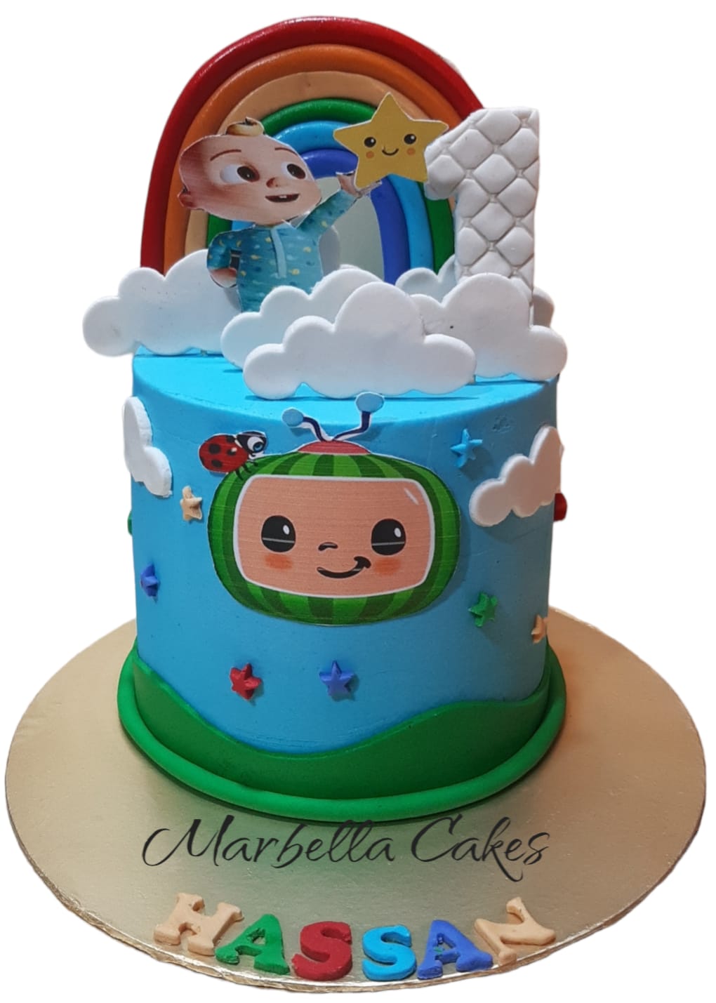 CoComelon Rainbow and Stars Cake with blue buttercream, fondant rainbow topper, JJ character cutout holding a star, number 1 topper, clouds, and personalized name letter board