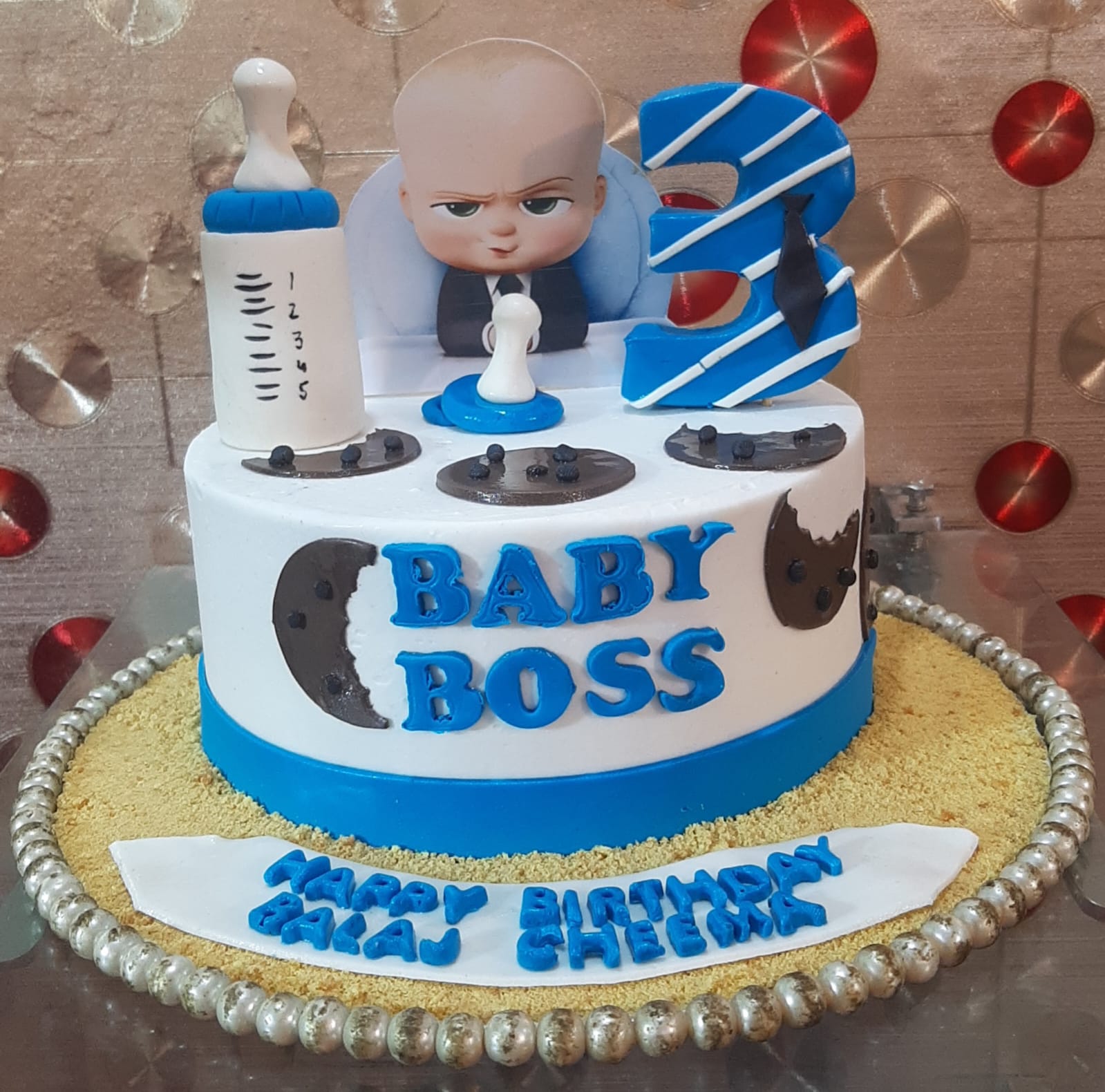 Baby Boss single-tier custom birthday cake with white and blue fondant, character topper and cookie decorations