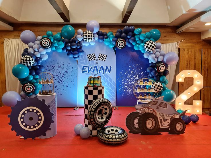 Monster truck racing birthday decoration with teal navy balloon arch, checkered flag balloons, tyre cutouts and marquee number