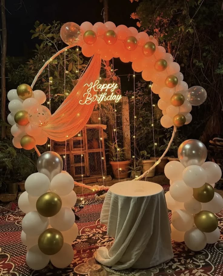 Outdoor birthday decoration with peach white gold balloon ring arch, Happy Birthday neon sign, fairy lights and balloon columns
