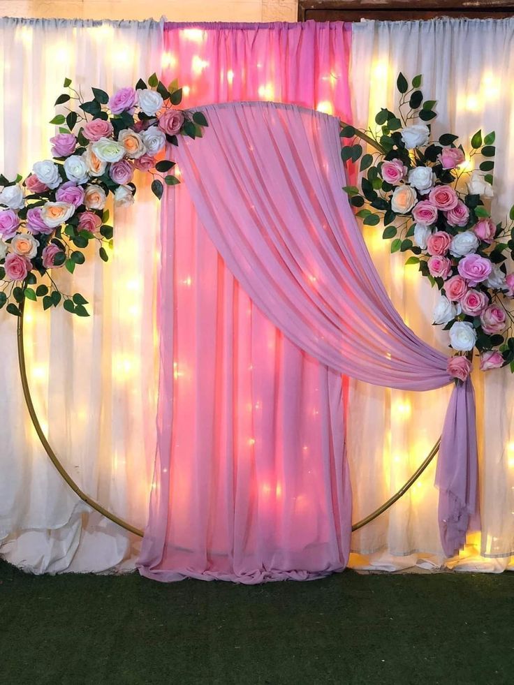 Pink floral ring backdrop decoration with gold circular frame, pink purple white roses, lavender chiffon drape and fairy lights backdrop