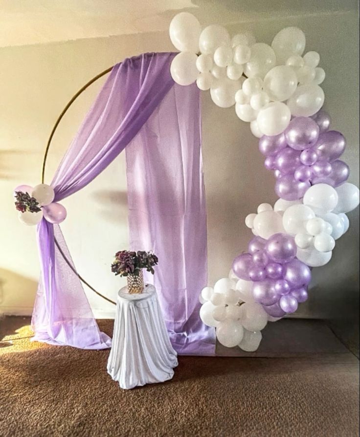 Lavender and white balloon ring arch decoration with gold circular frame, lavender chiffon drape and white dessert table