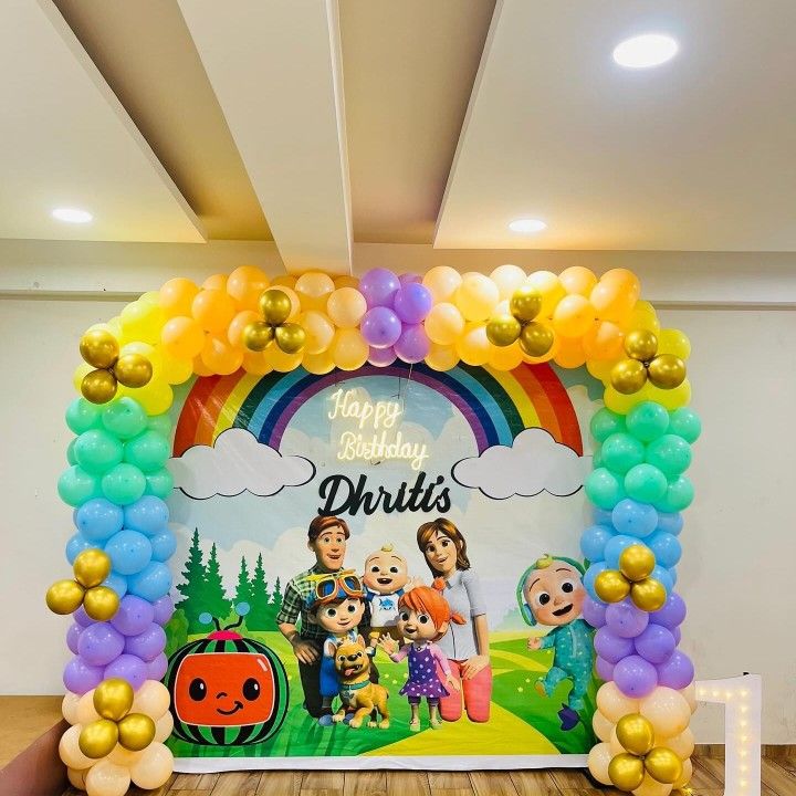 CoComelon birthday decoration with rainbow balloon arch columns, colorful pastel balloons and custom CoComelon family backdrop with Happy Birthday text