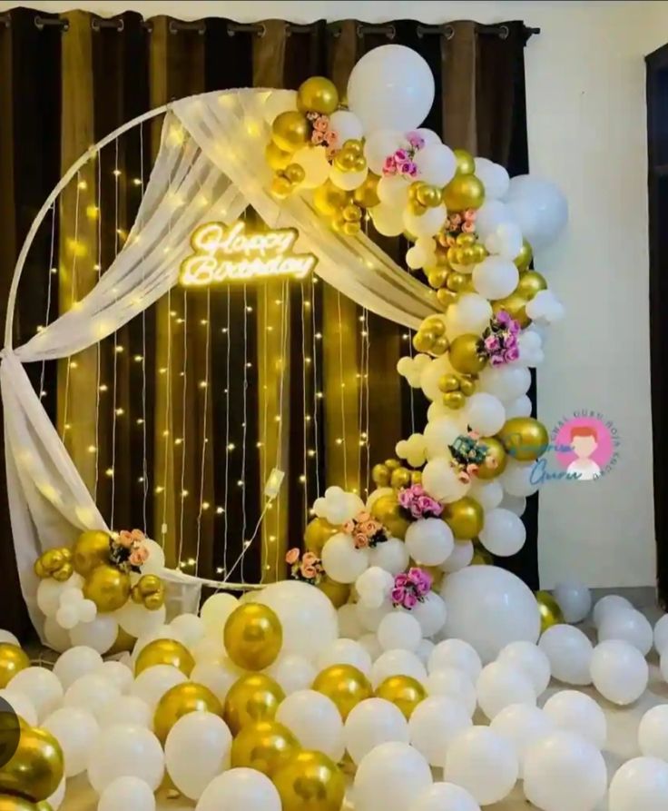 Gold and white birthday ring arch decoration with chrome gold white balloon garland, fairy string lights, Happy Birthday neon sign and floor filled with gold white balloons