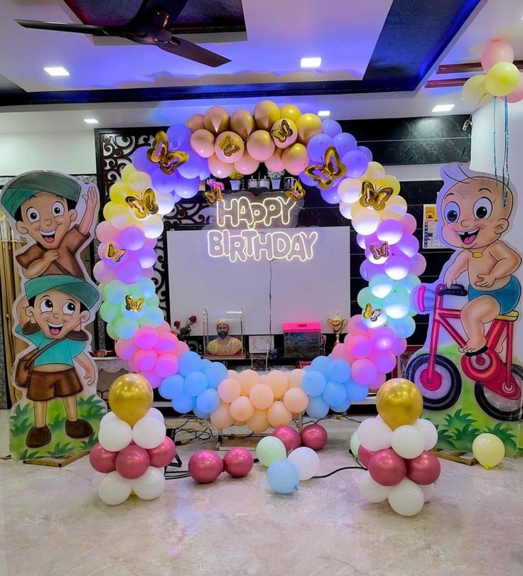 Chhota Bheem birthday decoration with pastel rainbow LED balloon arch, gold butterfly balloons, Happy Birthday neon sign and Bheem Chutki character cutout standees