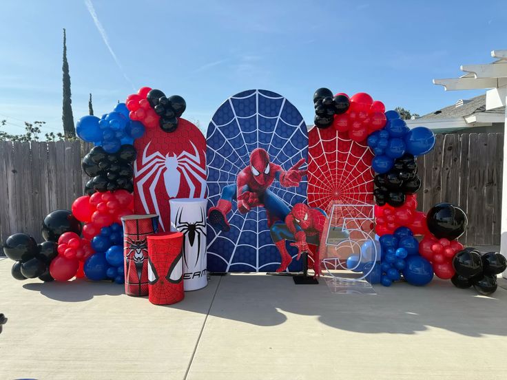 Spider-Man outdoor birthday decoration with red logo navy spiderweb triple panel backdrop, red blue black balloon garland and life-size Spider-Man standee