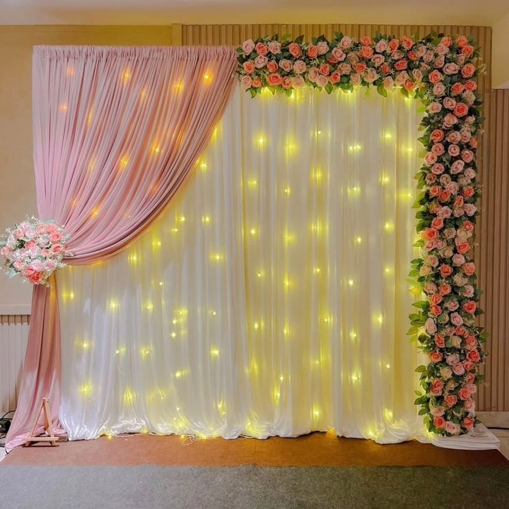 Pink and white floral fairy light backdrop with white sheer LED curtain, blush pink chiffon drape, pink white rose floral runner on top and cascading rose wall on the right side