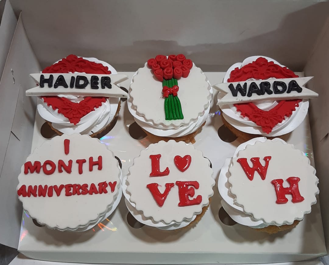 Box of 6 anniversary couple cupcakes in red and white fondant with personalized name banners, rose bouquet topper, LOVE lettering and couple initials
