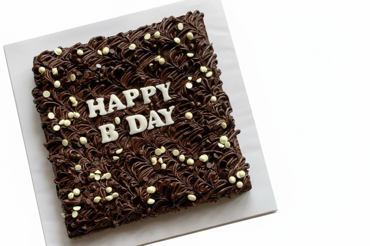 Personalised birthday brownie slab with chocolate swirl piping and fondant letters on white background
