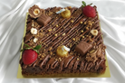 Luxury Ferrero brownie slab with strawberries, hazelnuts and gold decorations on white background