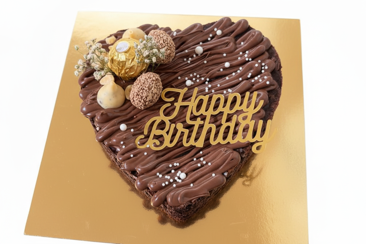 Heart-shaped Ferrero birthday brownie with gold topper and macarons on white background
