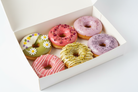 Floral glazed donut box with pastel colors and edible flowers on white background