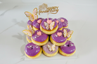 Happy Anniversary purple donut tower with butterfly decorations and gold topper on white background