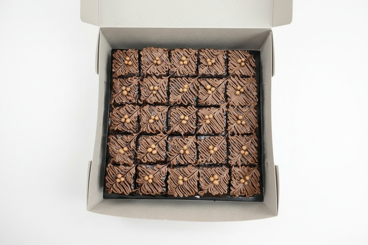 Decorated chocolate brownie slab box with feather piping and gold pearls on white background