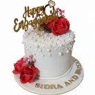White pearl texture engagement cake with red roses, gold Happy Engagement topper, and Sidra and Faisal name lettering on white background